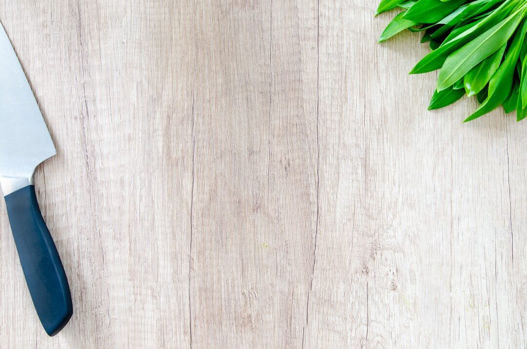 Wooden kitchen counter with cutting board, fresh herbs and cooking utensils
